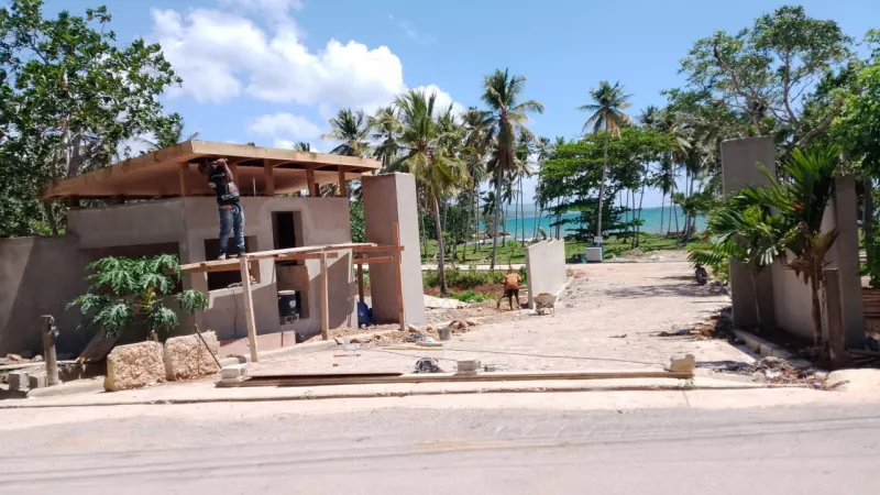 The entrance gatehouse under construction, with palms and the sea beyond